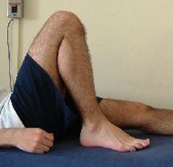 Photograph of a patient lying on their back with the leg pulled up into full flextion.