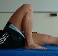 Photograph of a patient lying on their back with the leg pulled up into full flextion.