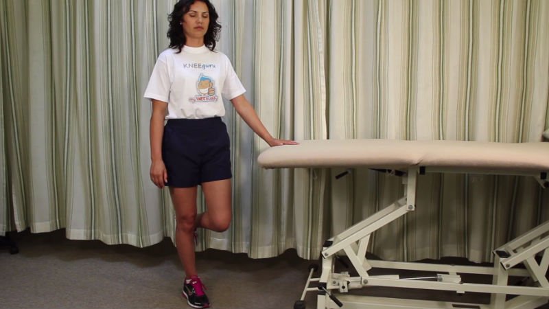 Patient standing on one leg, balancing with a hand held against a support.